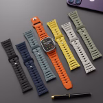 Bracelets Apple Watch EzStrap en silicone mat perforé, au style sport, déclinés en plusieurs couleurs, disposés à plat sur une surface noire à côté d’un stylo et d’un iPhone.