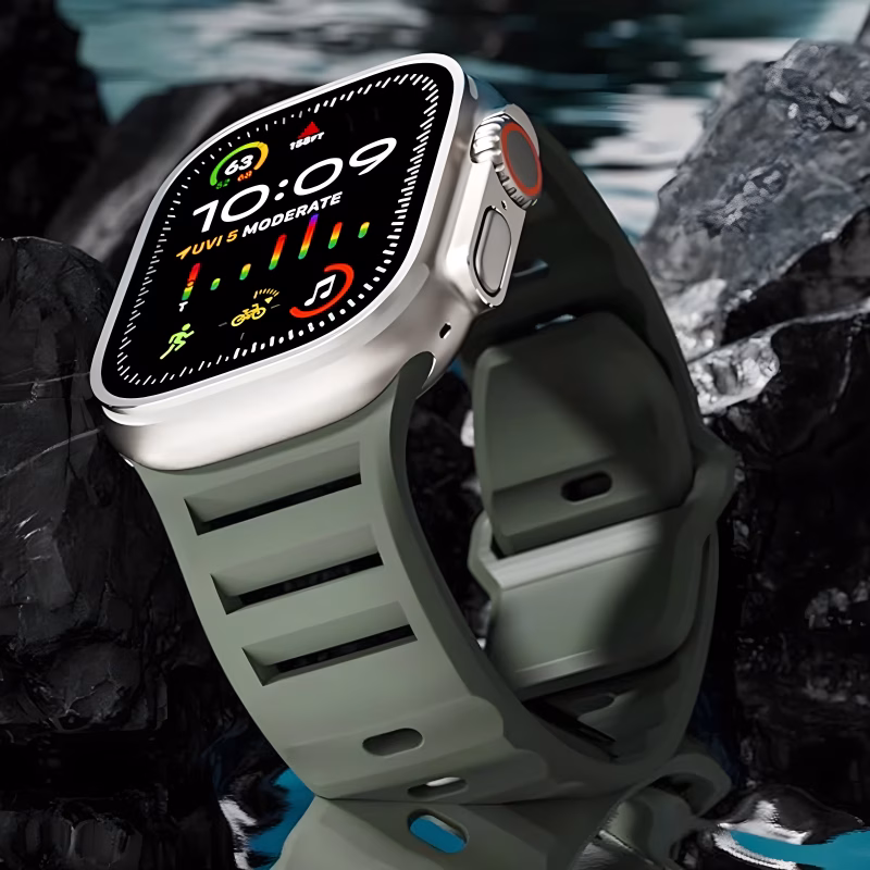 Bracelet Apple Watch EzStrap en silicone mat perforé de style sport, présenté en gros plan sur fond de roches sombres au bord de l’eau.