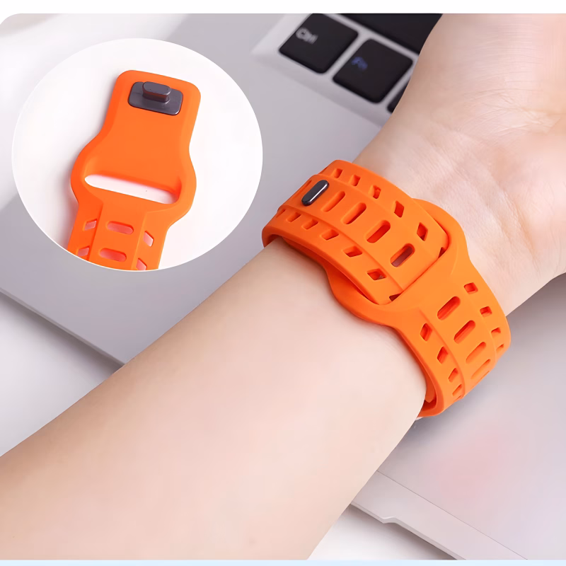 Bracelet Apple Watch EzStrap en silicone orange perforé, style sport, porté au poignet d’une personne devant un ordinateur portable.