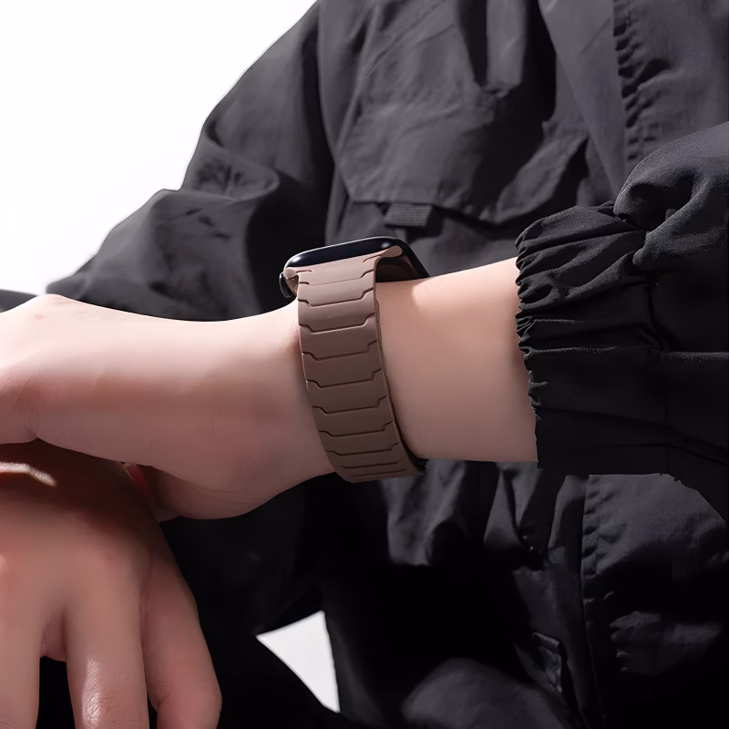 Bracelet Apple Watch EzStrap en silicone lisse marron, style sport à segments aimantés, porté au poignet d’une personne habillée en veste noire.