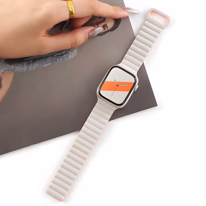 Bracelet Apple Watch EzStrap en silicone souple blanc à structure ondulée, de style sport, posé sur une surface blanche à côté d'une main féminine tenant un magazine.