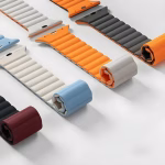 Bracelet Apple Watch EzStrap en silicone souple à structure ondulée, style sport, décliné en plusieurs couleurs, présenté enroulé et à plat sur une surface blanche.