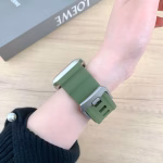 Bracelet Apple Watch EzStrap en silicone vert, au style sport avec fentes horizontales, porté au poignet d’une personne sur fond de table en bois clair.