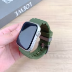 Bracelet Apple Watch EzStrap en silicone vert au style sport, avec fentes horizontales, tenu en main au-dessus d’une table en bois clair.