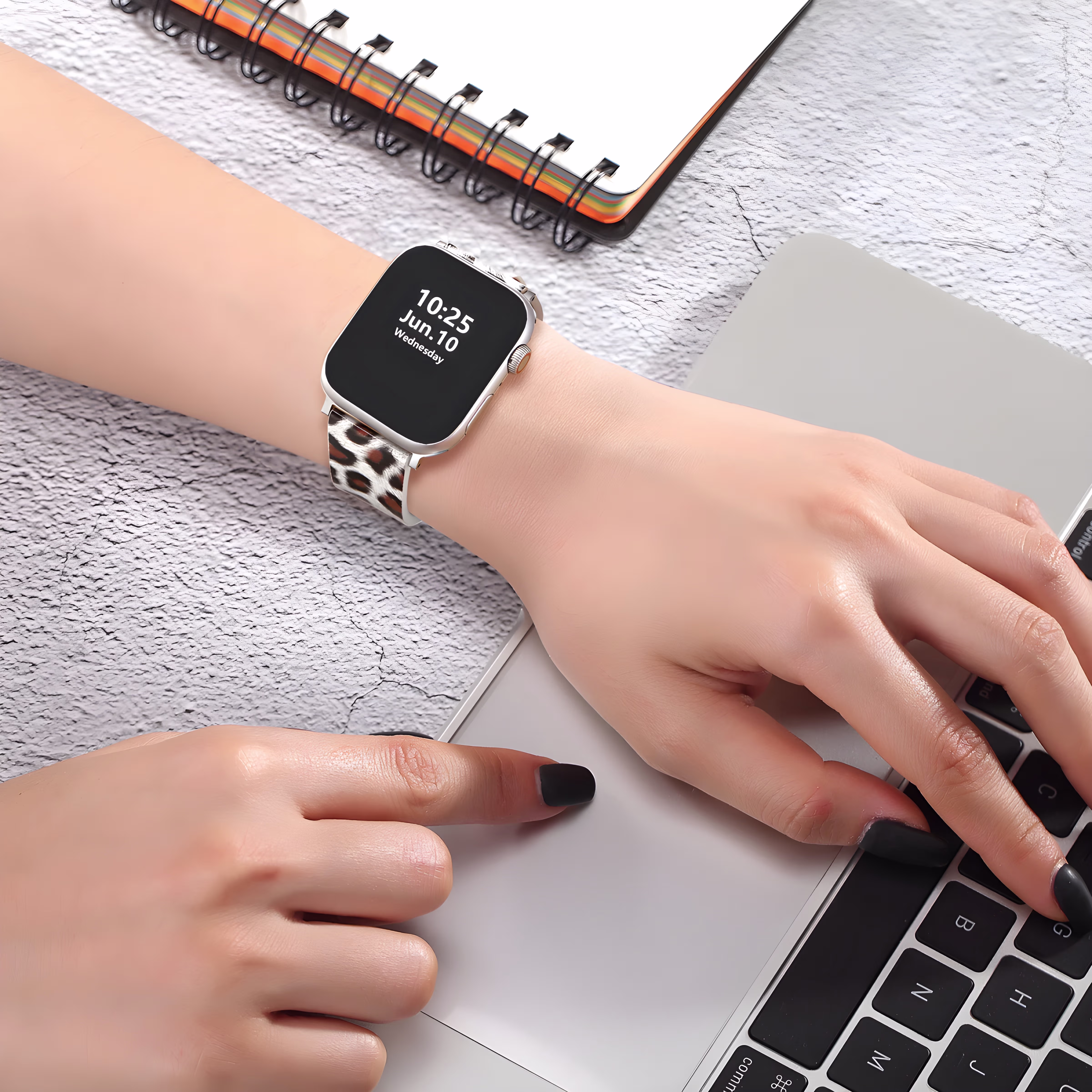 Bracelet Apple Watch EzStrap en cuir imprimé à motif léopard, de style élégant, porté au poignet d’une femme tapant sur un ordinateur portable.